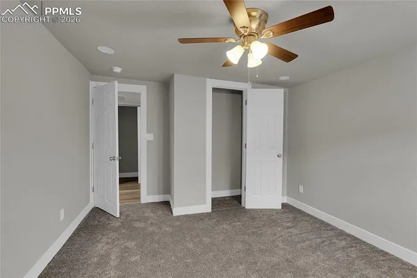 an empty room with closet and a ceiling fan