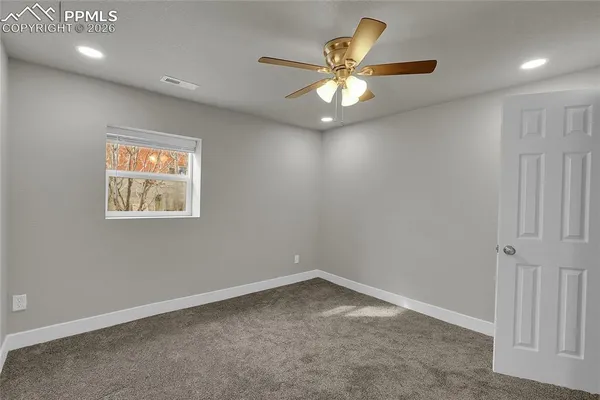 an empty room with a chandelier fan and windows