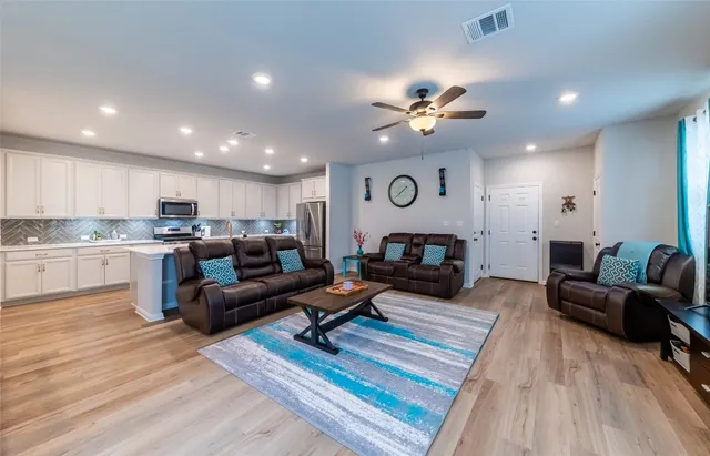 a living room with furniture kitchen view and a chandelier