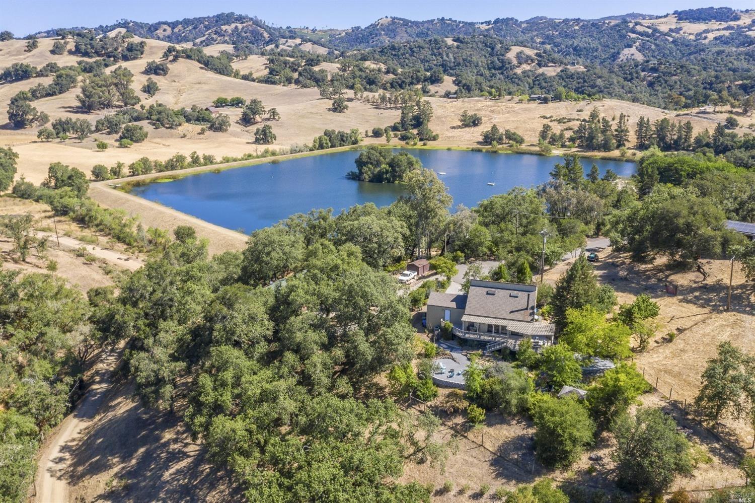 aerial view of a house with a yard and lake view