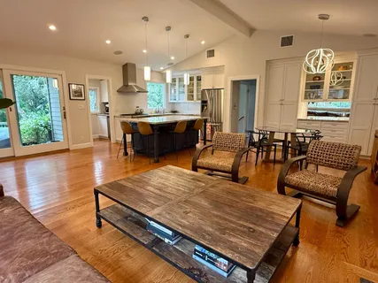 a living room with stainless steel appliances kitchen island granite countertop furniture and a wooden floor