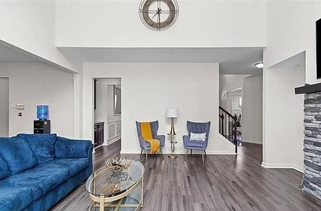 a living room with furniture a clock on wall and a table