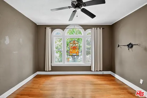 a view of an empty room with window and wooden floor