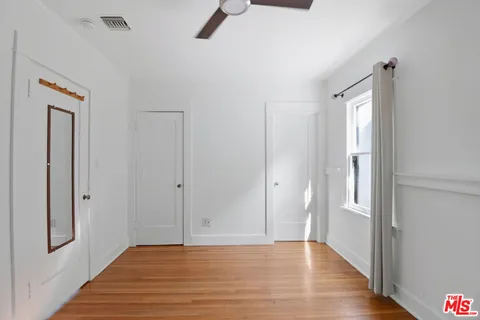 a view of an empty room with wooden floor and a window