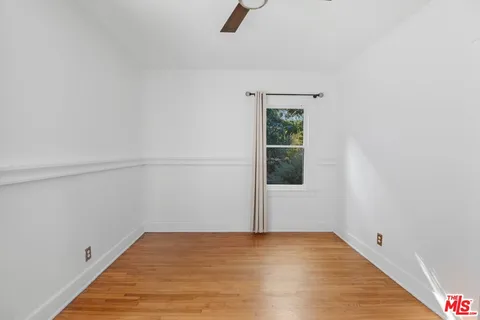 a view of an empty room with wooden floor and window