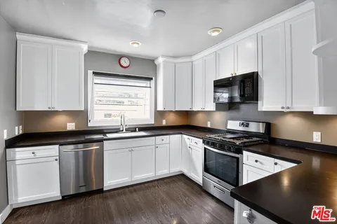 a kitchen with granite countertop a stove a sink and a microwave