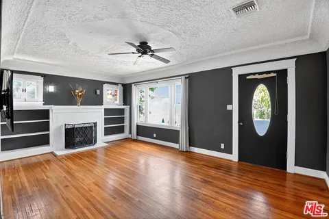 a view of a livingroom with a fireplace a ceiling fan and windows