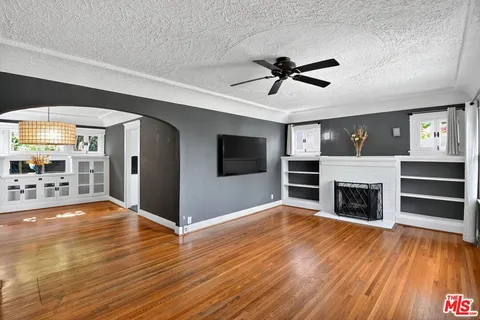 a view of a livingroom with a fireplace a ceiling fan a fireplace and entryway