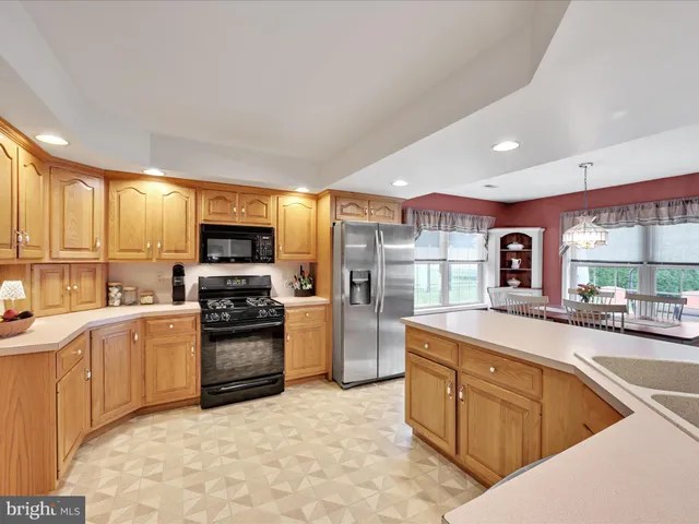 a kitchen with stainless steel appliances granite countertop a sink stove refrigerator and cabinets