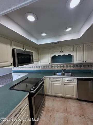 a kitchen with stainless steel appliances a sink a stove a microwave a sink and cabinets