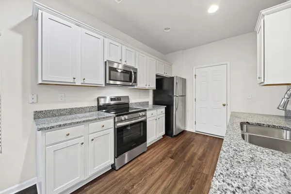a kitchen with stainless steel appliances granite countertop a stove a sink and a refrigerator