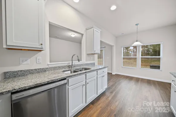 a kitchen with granite countertop a sink cabinets and wooden floor