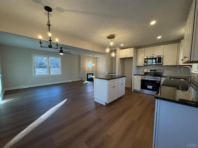 a large kitchen with stainless steel appliances granite countertop a stove a refrigerator a sink dishwasher and a oven with white cabinets