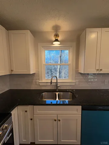a kitchen with granite countertop a sink cabinets and window