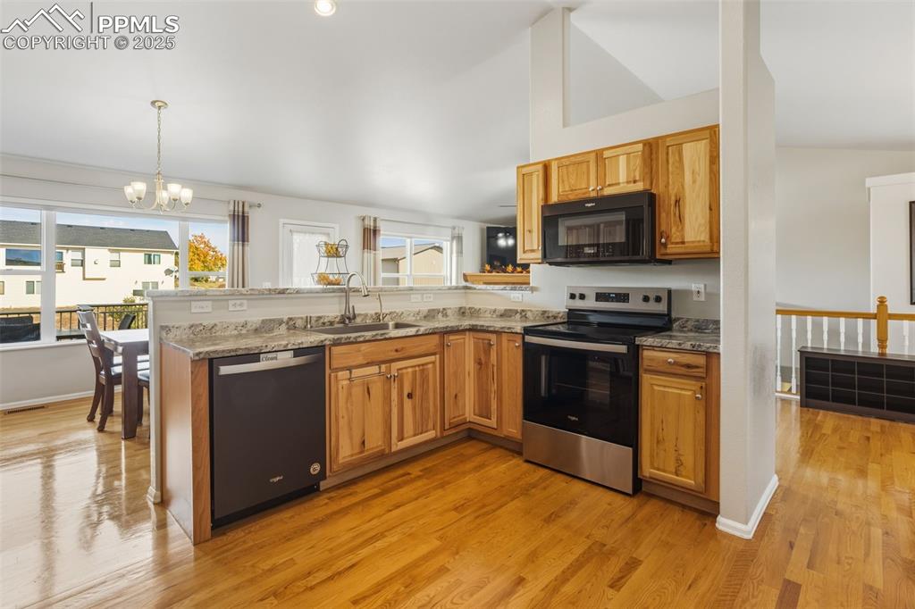 8449 Copenhagen Road Peyton, CO 80831 - Photo 18 of 49 a kitchen with stainless steel appliances granite countertop a stove top oven a sink dishwasher a dining table and chairs with wooden floor