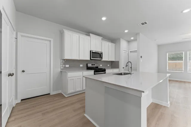 a kitchen with a sink a microwave a stove and cabinets