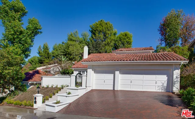 a front view of a house with a yard and potted plants