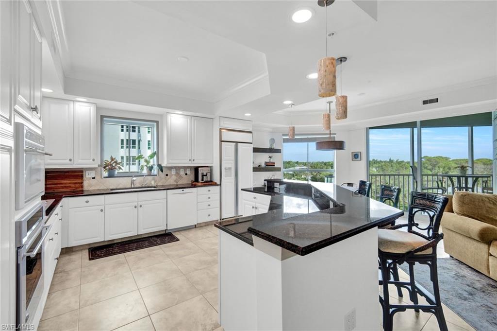 295 Grande Way, Unit 306 Naples, FL 34110 - Photo 11 of 48 a kitchen with stainless steel appliances kitchen island granite countertop a table chairs and a view of living room