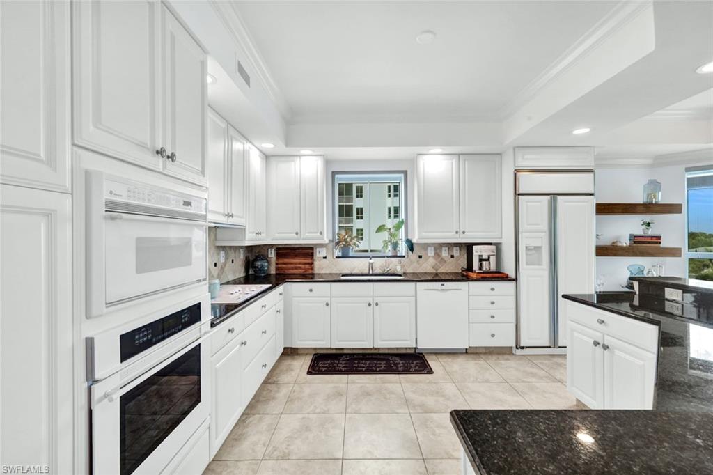 295 Grande Way, Unit 306 Naples, FL 34110 - Photo 12 of 48 a kitchen with granite countertop white cabinets and stainless steel appliances