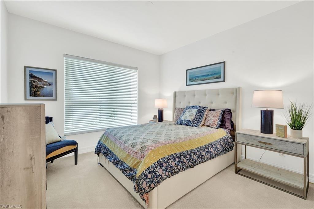 295 Grande Way, Unit 306 Naples, FL 34110 - Photo 26 of 48 a bedroom with a bed and a lamp on table