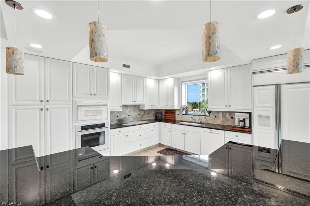 295 Grande Way, Unit 306 Naples, FL 34110 - Photo 10 of 48 a kitchen with granite countertop white cabinets and stainless steel appliances