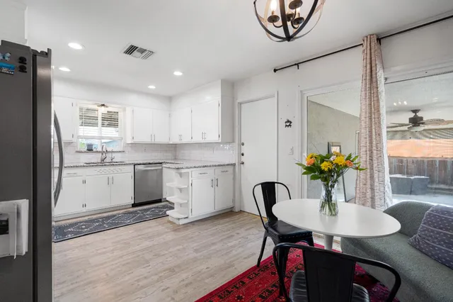 a kitchen with a table chairs a sink dishwasher and cabinets