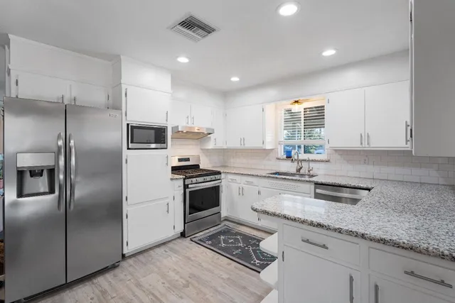 a kitchen with granite countertop a sink stainless steel appliances and window