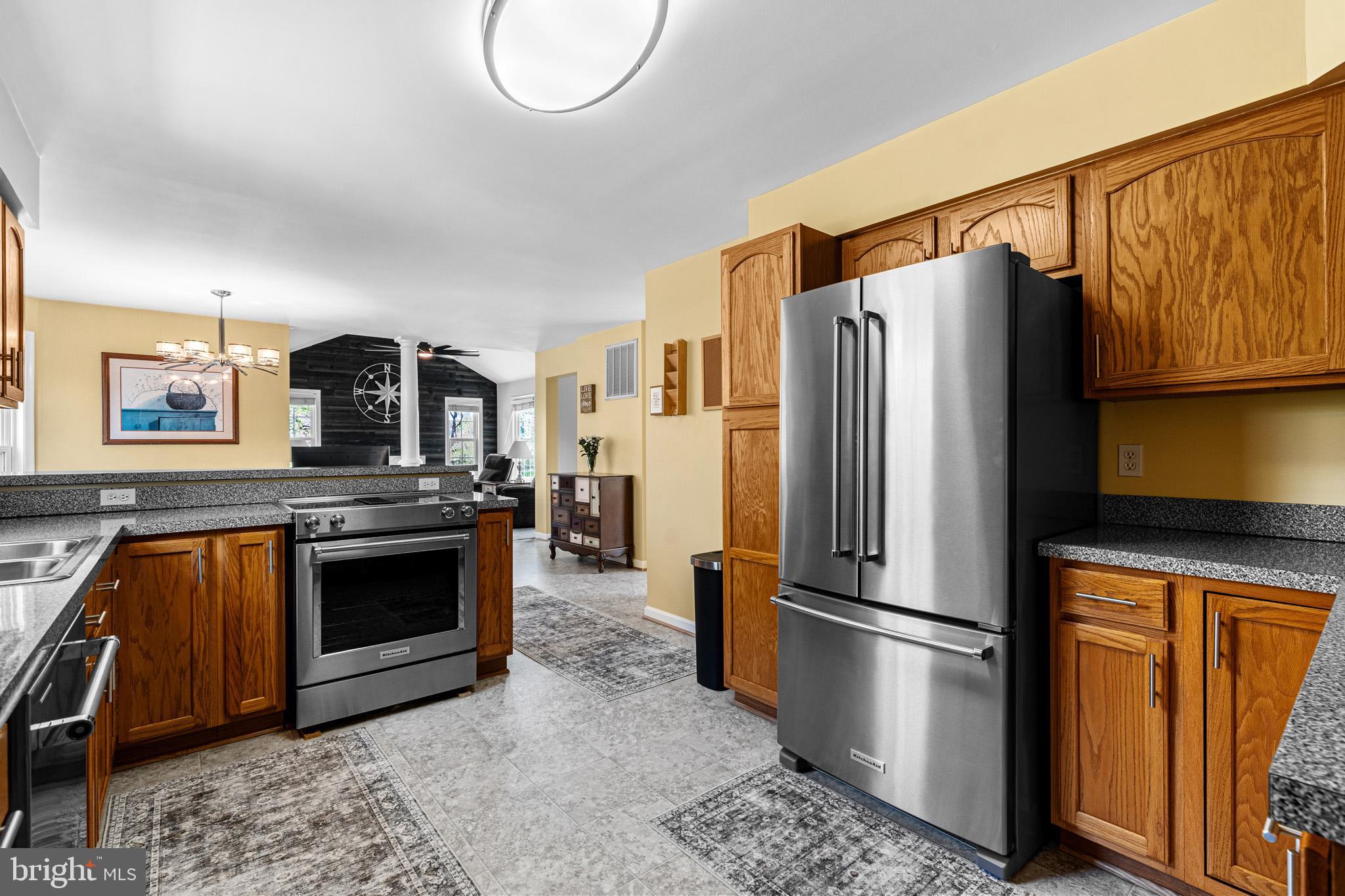 1230 Plum Point Road Huntingtown, MD 20639 - Photo 23 of 79 a kitchen with stainless steel appliances granite countertop a refrigerator a stove and a sink with wooden floor