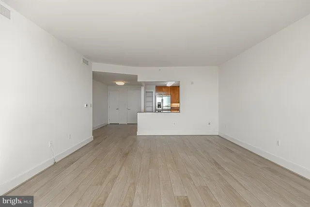 an empty room with wooden floor and a hallway