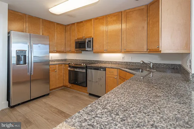 a kitchen with stainless steel appliances granite countertop a stove a sink and a refrigerator