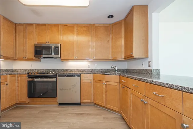 a kitchen with granite countertop cabinets stainless steel appliances and a counter space