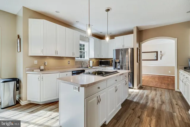 a kitchen with wooden floor white cabinets and stainless steel appliances