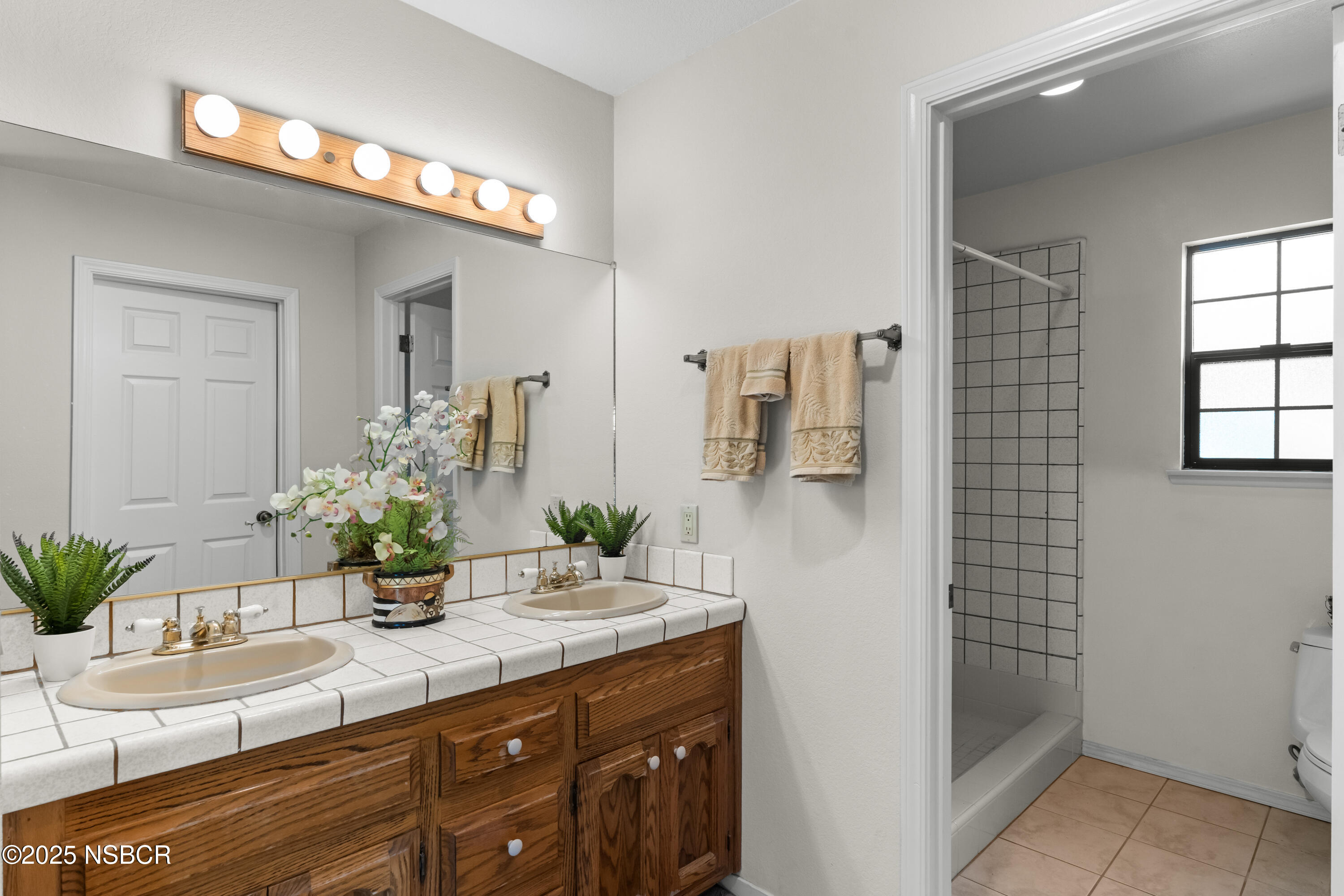 181 Eucalyptus Road Nipomo, CA 93444 - Photo 21 of 36 a bathroom with a granite countertop sink a mirror and a shower