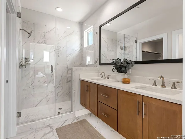 a bathroom with a double vanity sink mirror and shower
