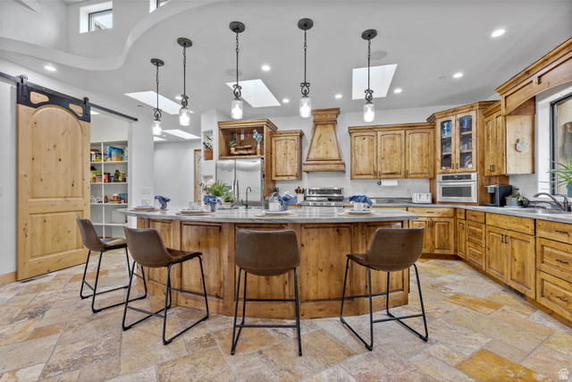 98 Bridge Road Rockville, UT 84763 - Photo 14 of 75 Kitchen with glass insert cabinets, an island with sink, a skylight, brown cabinets, and a kitchen breakfast bar