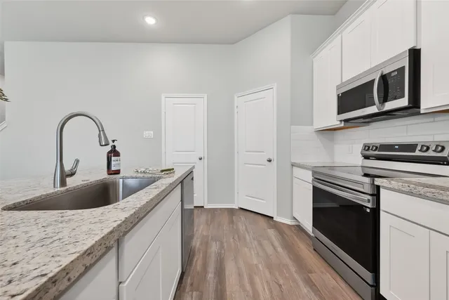 a kitchen with stainless steel appliances granite countertop a sink a stove and microwave