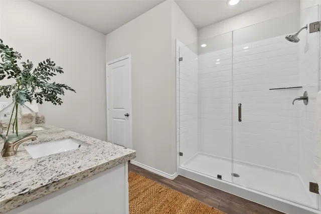 a bathroom with a granite countertop sink a mirror and shower