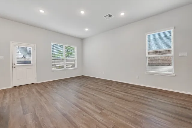 an empty room with wooden floor and windows