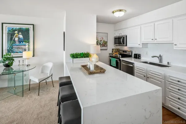 a kitchen with stainless steel appliances a stove a sink a microwave a refrigerator a dining table and chairs with wooden floor