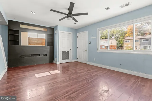 a view of empty room with wooden floor and fan