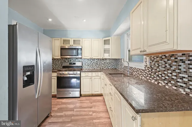 a kitchen with granite countertop a refrigerator and a stove top oven
