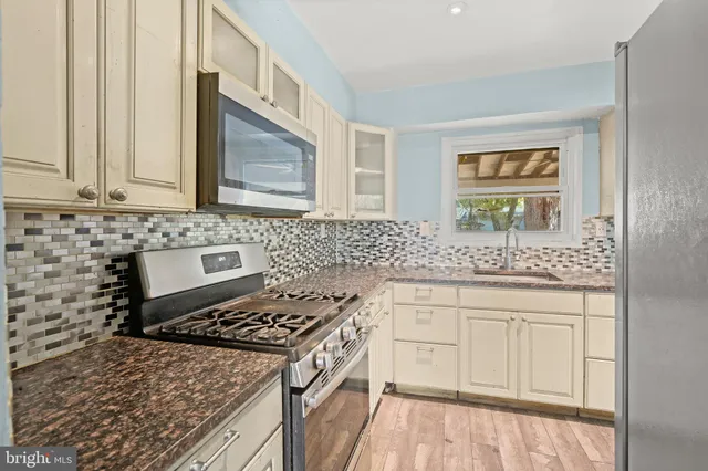 a kitchen with granite countertop a sink stove and cabinets