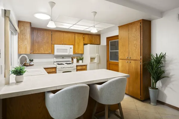 a kitchen with stainless steel appliances granite countertop a dining table chairs refrigerator and sink