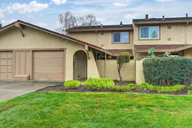 a front view of a house with a yard and potted plants