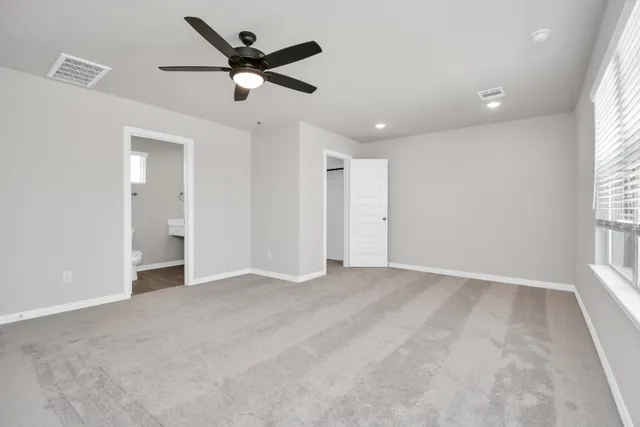 a view of an empty room and a ceiling fan and window