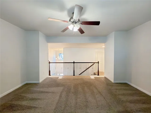 an empty room with windows and ceiling fan