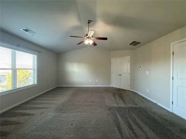 an empty room with chandelier fan and windows