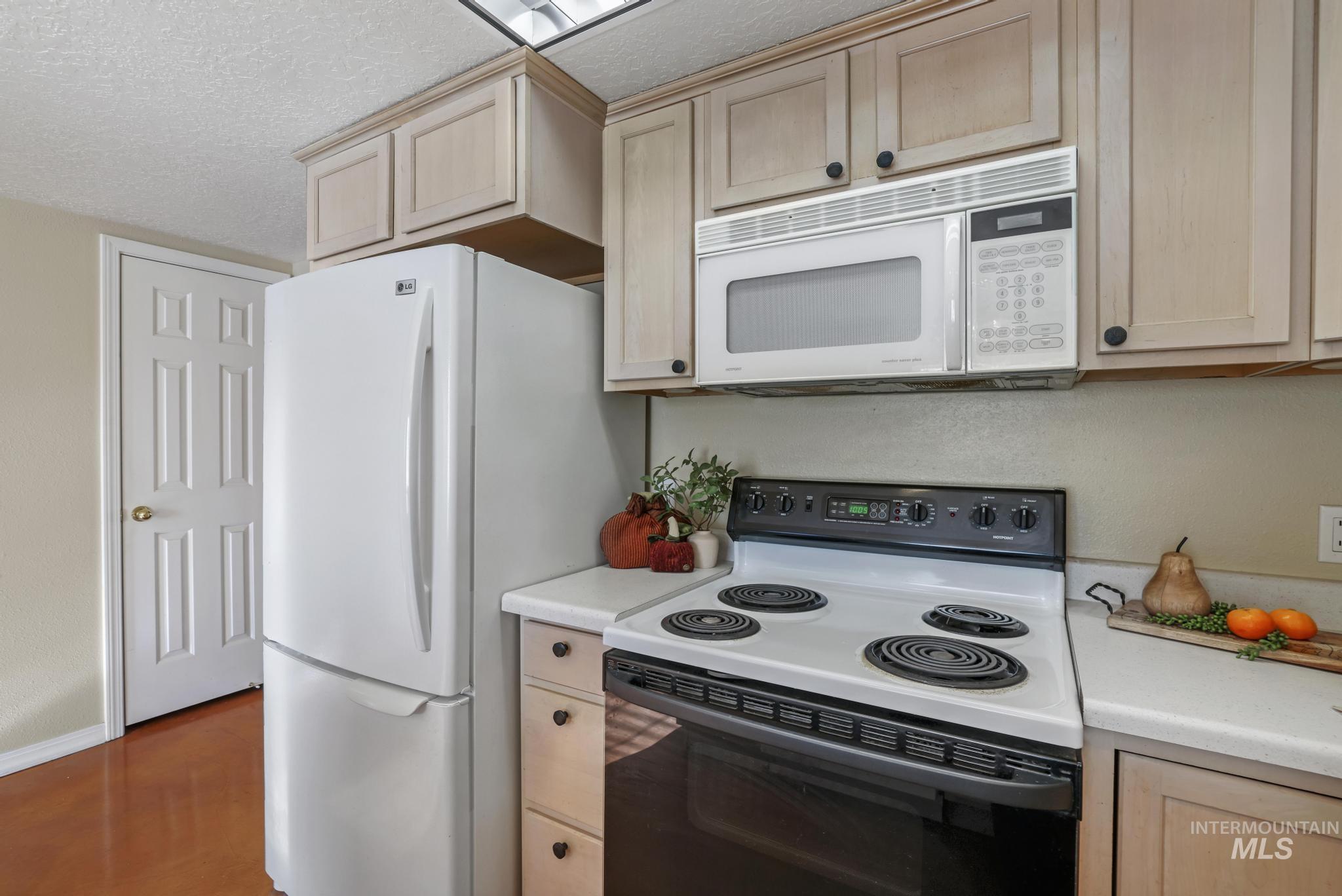 1935 Hampton Way Twin Falls, ID 83301 - Photo 11 of 25 Kitchen with white appliances, light countertops, light brown cabinets, and a textured ceiling