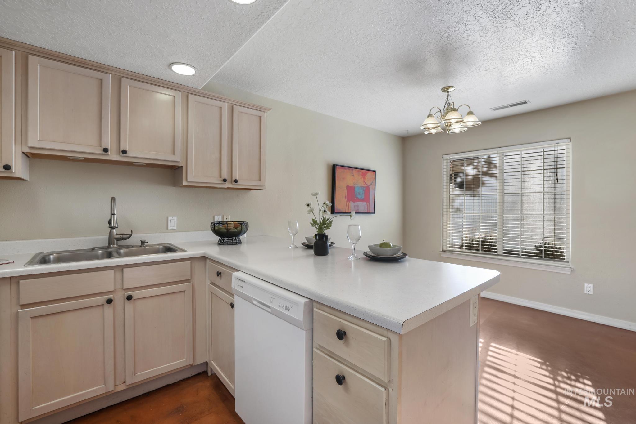 1935 Hampton Way Twin Falls, ID 83301 - Photo 12 of 25 Kitchen featuring light countertops, dishwasher, light brown cabinetry, a peninsula, and a textured ceiling