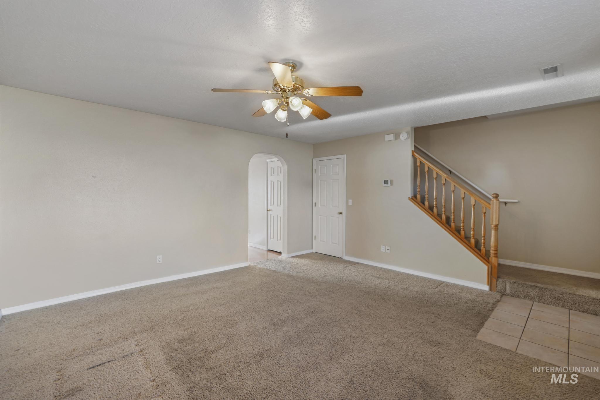 1935 Hampton Way Twin Falls, ID 83301 - Photo 17 of 25 Carpeted empty room with arched walkways, stairs, and ceiling fan